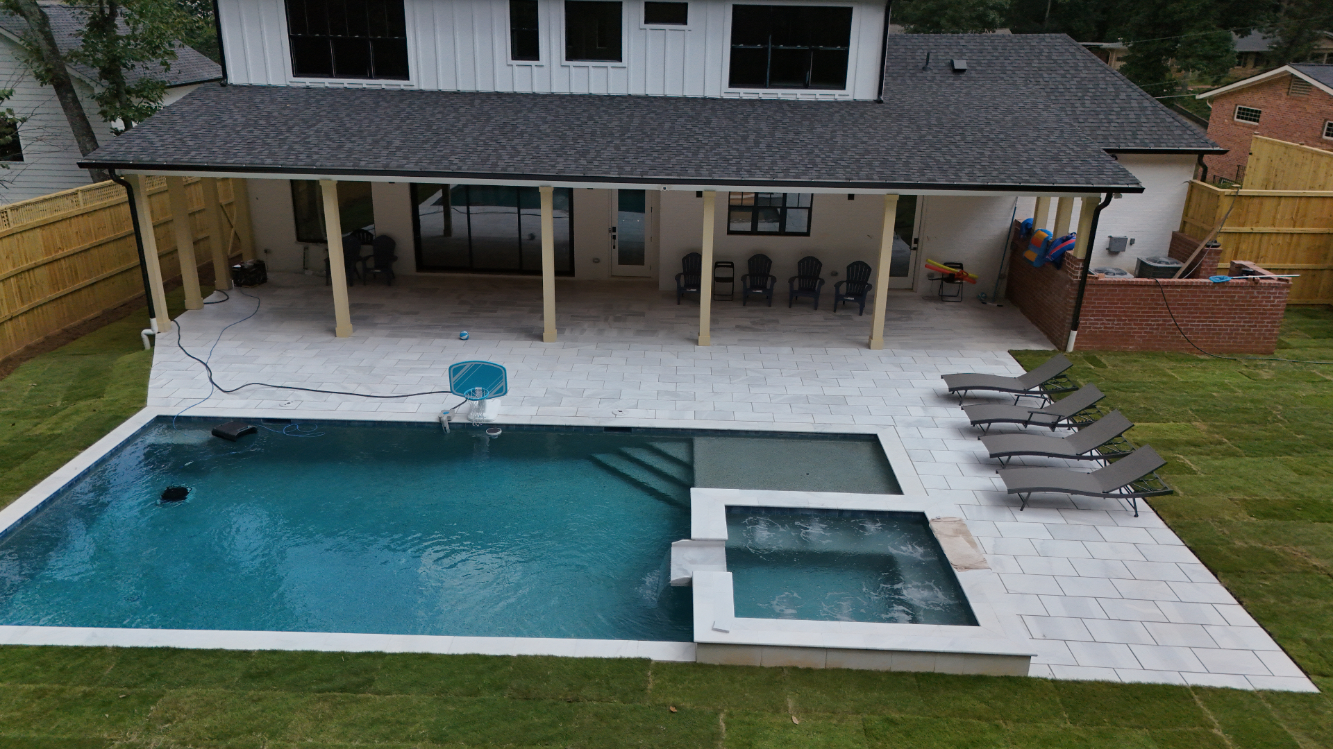 Custom pool, spa, and large paver patio with home in background