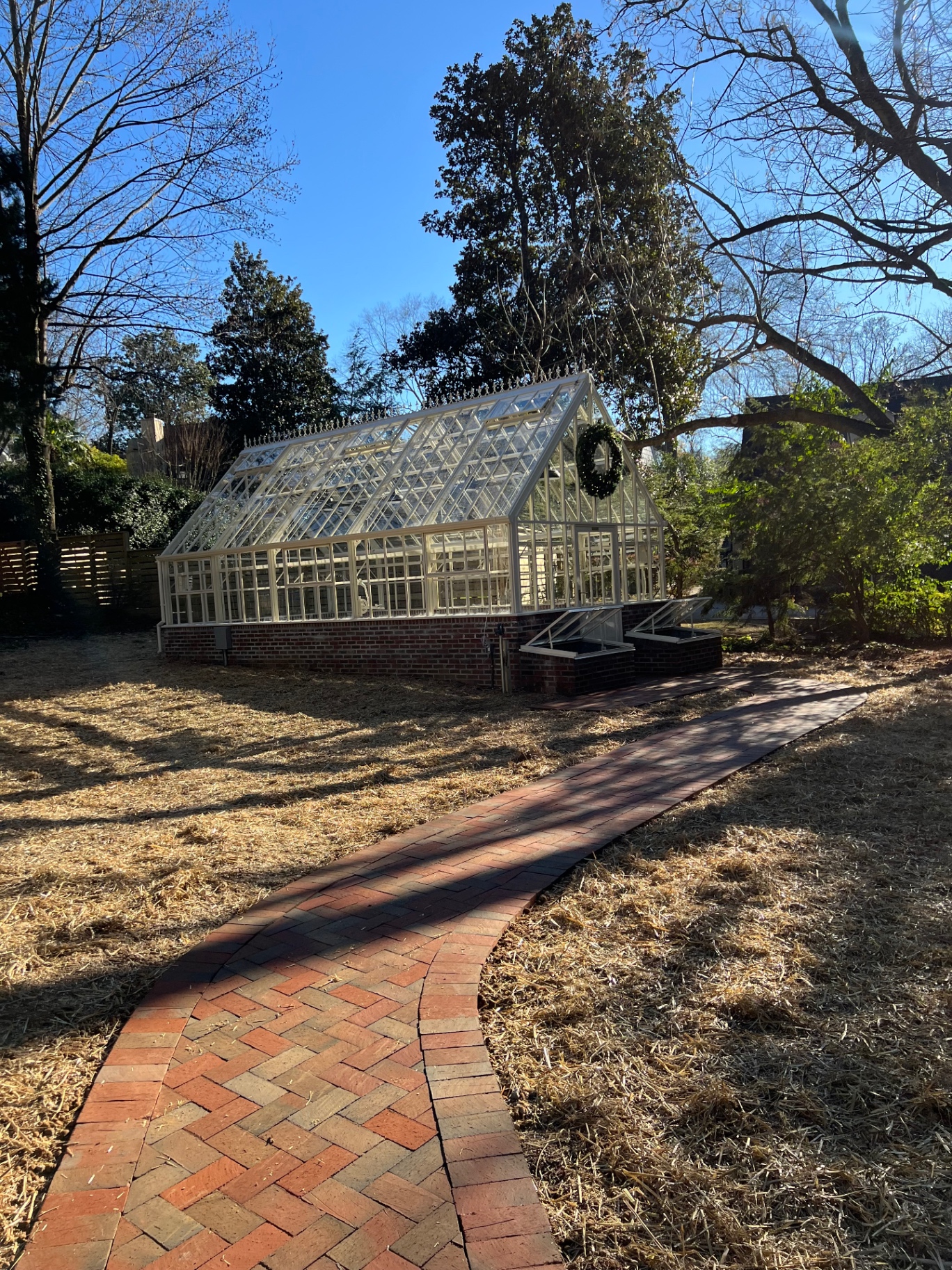 Side view of greenhouse with a curved brick path leading to the structure
